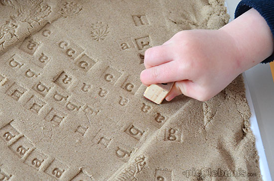 Stamping with alphabet stamps into kinetic sand
